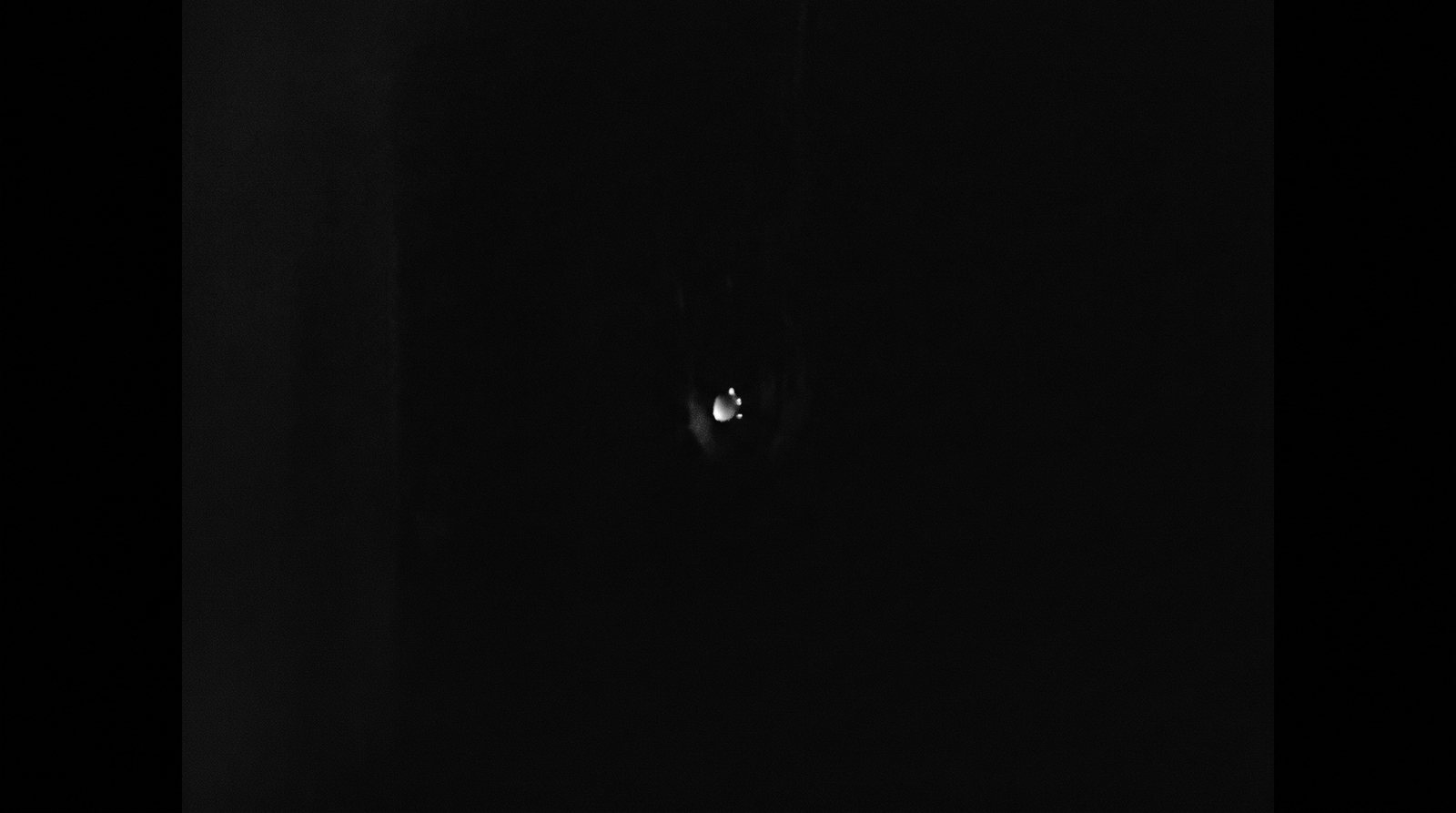 A single dying ember glowing faintly in near-total darkness